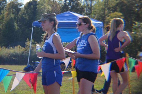 High school cross country runners Olivia Plunkett and Blair King wait at the finish line for the middle school girls to cross.